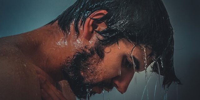 dark image of young, healthy man's profile in the shower