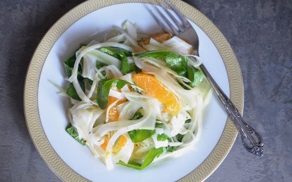 15 Minute Shaved Fennel Citrus Salad 1 shaved fennel salad with citrus and arugula on a white plate with gold trim and a fork angled on the righthand side