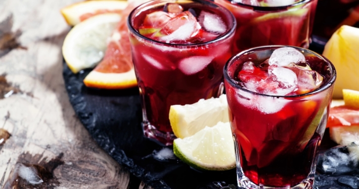 Red Wine Citrus Sangria Recipe 1 three glasses of red wine citrus sangria on a black tray with wedges of citrus for accents
