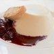 Vanilla Bean Panna Cotta on a white plate with berries and berry coulis