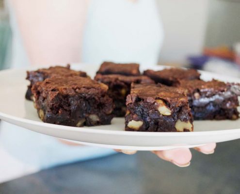 gluten-free chocolate chunk brownies on a white plate being held by a woman's hand