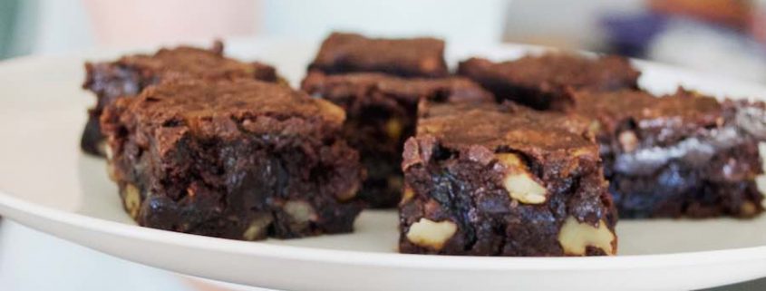 gluten-free chocolate chunk brownies on a white plate being held by a woman's hand