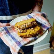 Pumpkin Coffee Cake from Eat Cake Naked being held by two hands on a white plate with a plaid tea towel