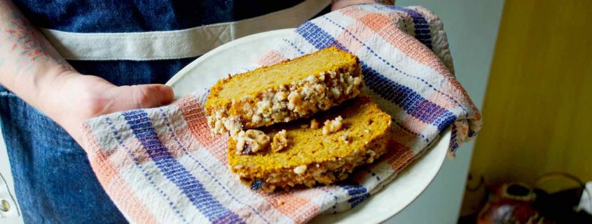 Pumpkin Coffee Cake from Eat Cake Naked being held by two hands on a white plate with a plaid tea towel