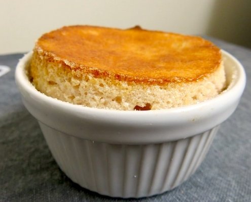 Closeup of Annette's lemon soufflé in a while ramekin on a gray background