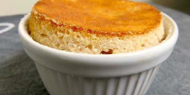 Closeup of Annette's lemon soufflé in a while ramekin on a gray background