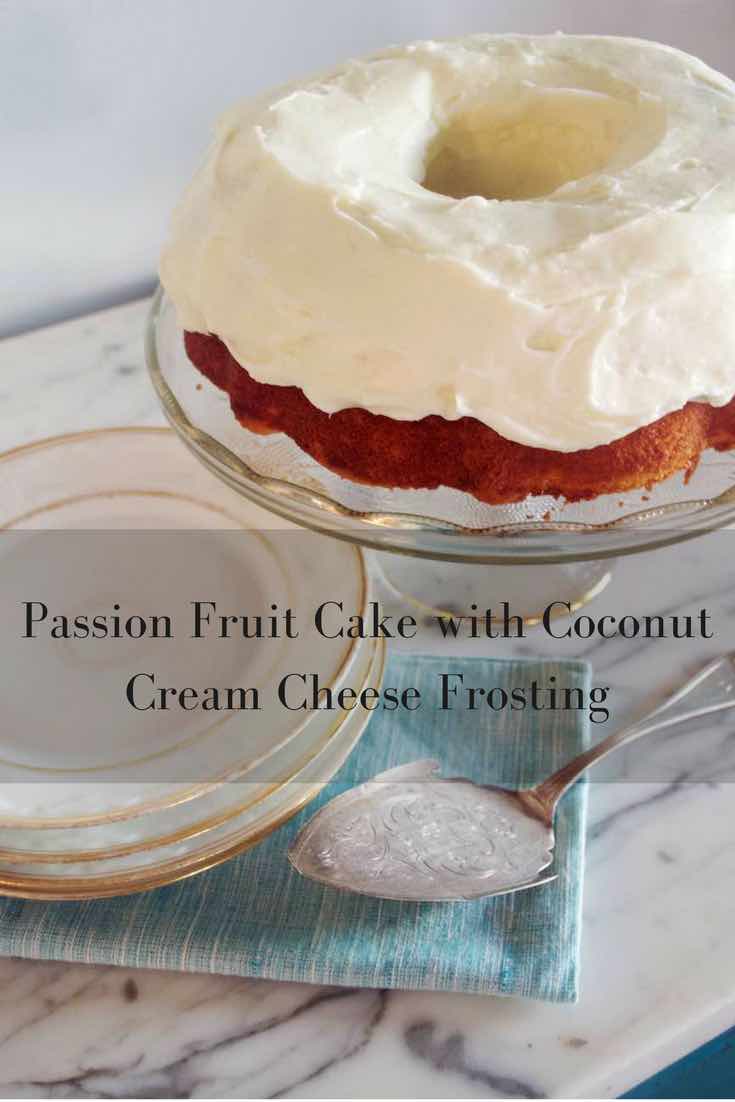 Closeup  of Passion Fruit Bundt Cake with Coconut Cream Cheese Frosting on a crystal cake plate with a stack of white plates in the background