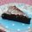 Slice of Sharffen Berger gluten free Chocolate Cake on a blue plate with white polkadots and floral trip on a pink tablecloth