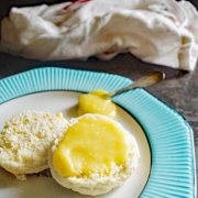 passion fruit curd on a scone sitting on a white plate with turquoise trim