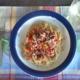 whole wheat spaghetti with raw tomato sauce on a plaid placemat with a glass of white wine