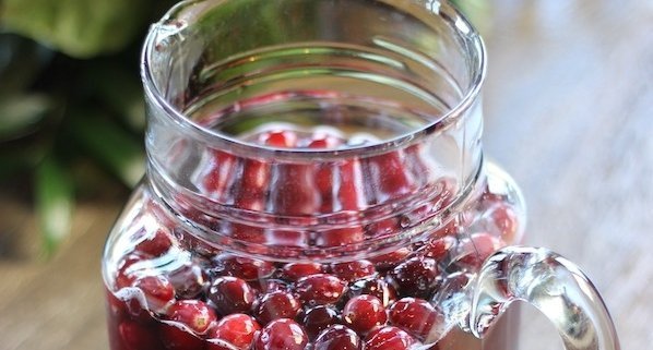 sparking Christmas punch in a large, glass jar with fresh cranberries floating on top