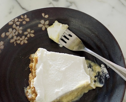 closeup of Crazy Sexy Key Lime Pie on a black plate with a faint floral pattern on top of a white marble counter