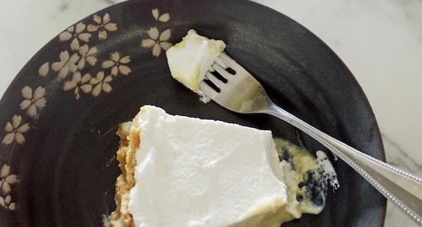 closeup of Crazy Sexy Key Lime Pie on a black plate with a faint floral pattern on top of a white marble counter