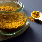 a glass jar of powdered turmeric with a spoon to illustrate the sex benefits of turmeric