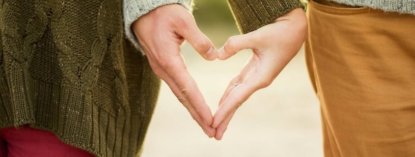 a couple making a heart with their hands