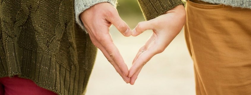 a couple making a heart with their hands