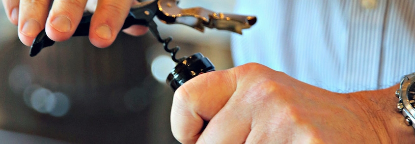 a closeup of a male sommelier opening a bottle of Pinot Noir at the World of Pinot Noir wine festival