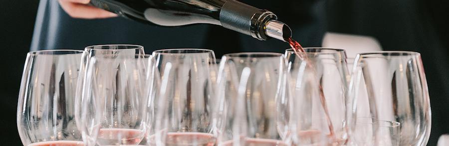 Sommelier pouring wine into multiple glasses at World of Pinot Noir event