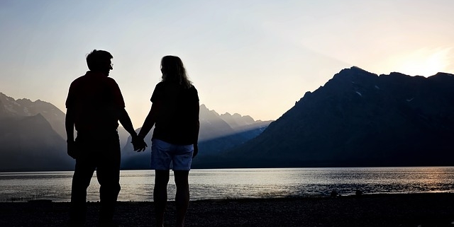 Romantic travel image of couple holding hands in the mountains at sunset