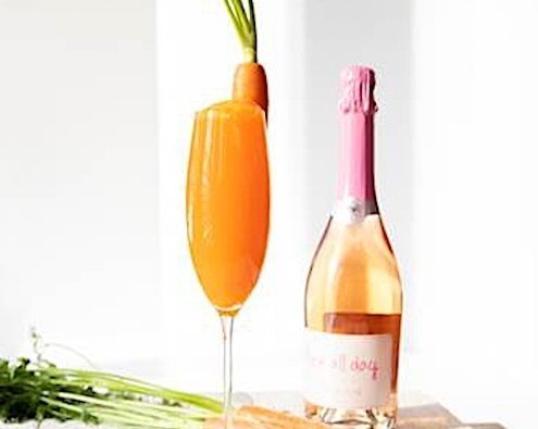 Closeup of Easter Cocktail in Champagne flute with bottle of sparking wine behind it on white background