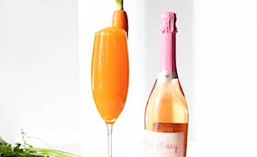 Closeup of Easter Cocktail in Champagne flute with bottle of sparking wine behind it on white background