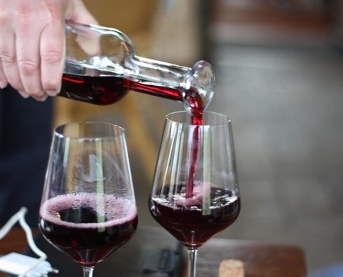 Wine being poured from a bottle into two glasses