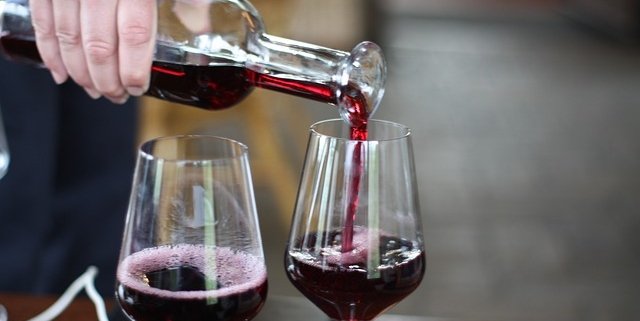Wine being poured from a bottle into two glasses