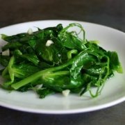 closeup of garlicky pea tendrils on a white plate