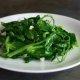 closeup of garlicky pea tendrils on a white plate