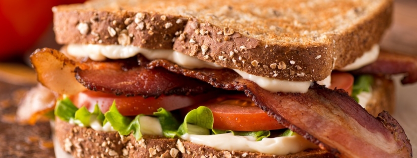 Closeup of a bacon, tomato and avocado picnic sandwich on whole grain bread
