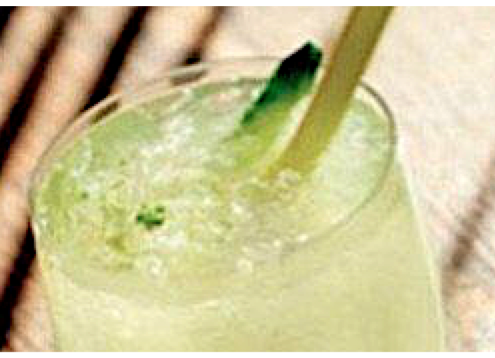 closeup of coconut limeade cocktail on a brown striped background