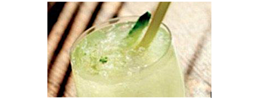 closeup of coconut limeade cocktail on a brown striped background