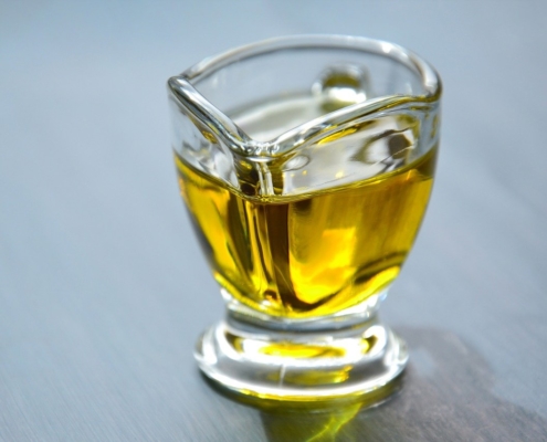 avocado oil in a glass pitcher on a blue background to illustrate the benefits of avocado oil