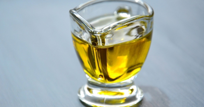 avocado oil in a glass pitcher on a blue background to illustrate the benefits of avocado oil