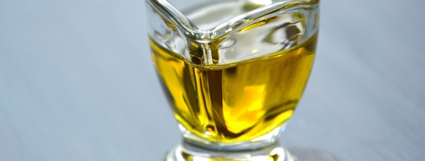 avocado oil in a glass pitcher on a blue background to illustrate the benefits of avocado oil