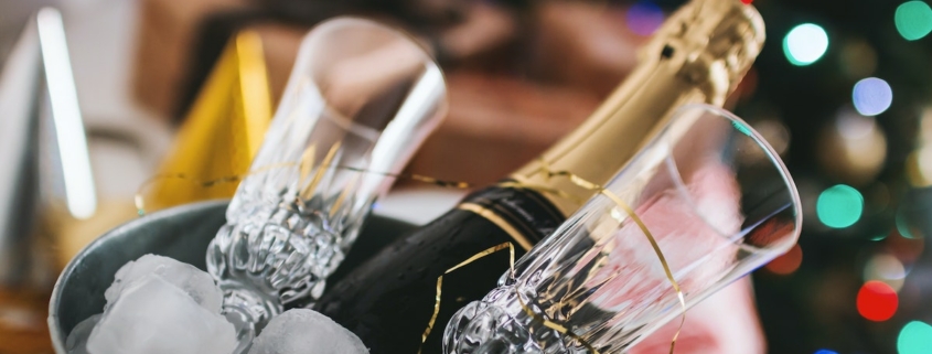 Bottle of champagne and two champagne flutes chilling in an ice bucket in front of a christmas tree