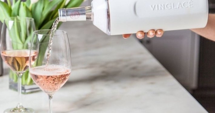 Best Wine Bottle Chiller: Why I Still Recommend the Vinglacé 1 wine being poured from a white Vinglacé wine cooler into a wine glass on a marble counter with tulips in the background