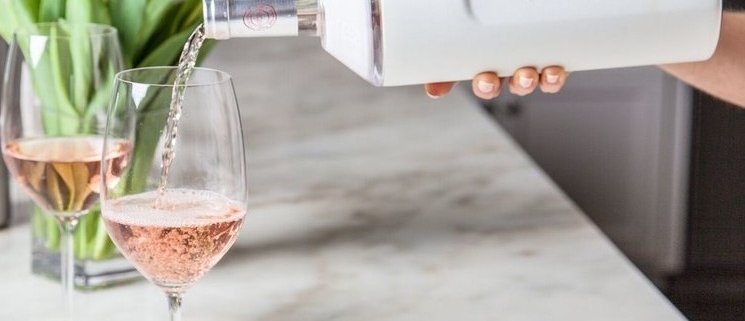 wine being poured from aVinglace wine cooler into a wine glass with tulips in the background