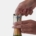 a pair of hands putting a gold metallic rabbit champagne stopper on a bottle of sparkling wine