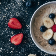 overnight steel cut oats in a white bowl with bananas and blueberries on top and strawberry slices on the side