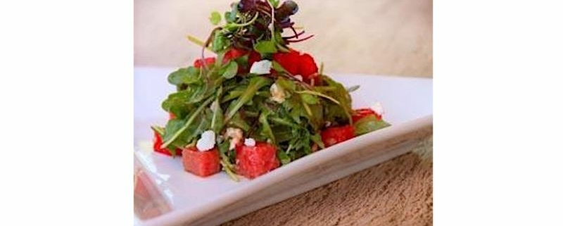 Closeup of grilled watermelon salad with arugula on a white plate