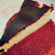 Burnt Basque Cheesecake with a red sauce on a white plate