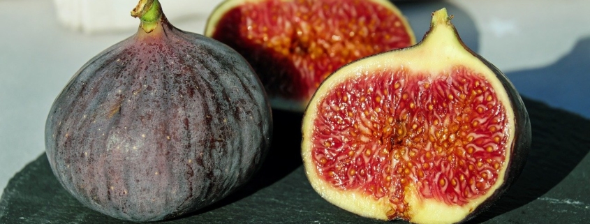 two figs, one cut in half as an illustration of the benefits of figs