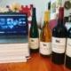 computer open to a Zoom wine tasting with a lineup of wine bottles beside it