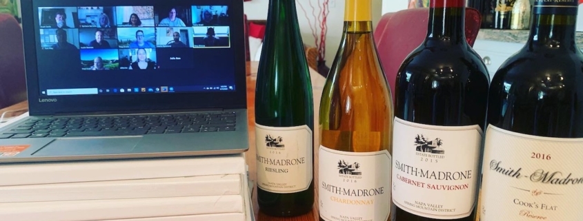 computer open to a Zoom wine tasting with a lineup of wine bottles beside it