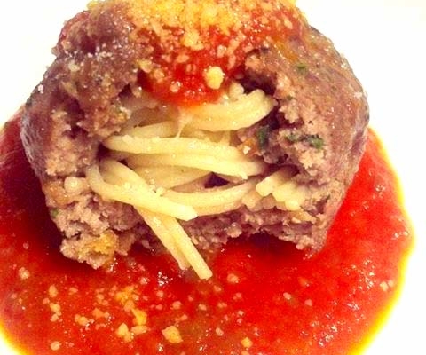Spaghetti-Stuffed Meatballs Recipe 8 closeup of giant meatball stuffed with spaghetti in marinara sauce on a white plate