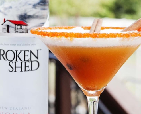 pumpkin apple cider cocktail in a martini glass with a bottle of Broken Shed vodka in the background