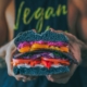 a pair of hands holding a colorful vegan sandwich