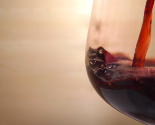 red wine being poured into a pinot noir glass