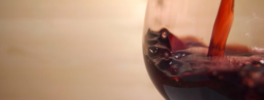 red wine being poured into a pinot noir glass